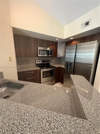 a kitchen with stainless steel appliances kitchen island granite countertop a sink and a stove