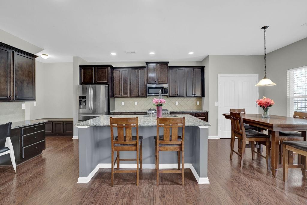 333 Nobleman Way Canton, GA 30114 - Photo 11 of 31 a kitchen with stainless steel appliances granite countertop a dining table chairs refrigerator and microwave