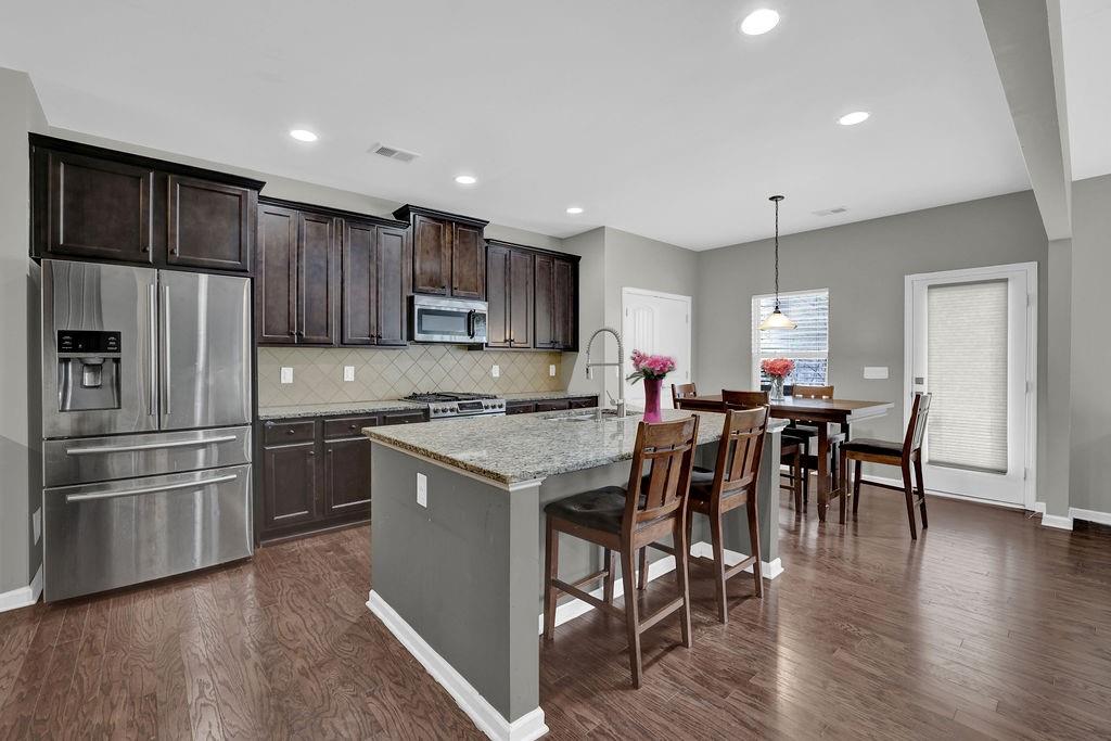 333 Nobleman Way Canton, GA 30114 - Photo 12 of 31 a kitchen with stainless steel appliances granite countertop a refrigerator a stove a sink a dining table and chairs with wooden floor