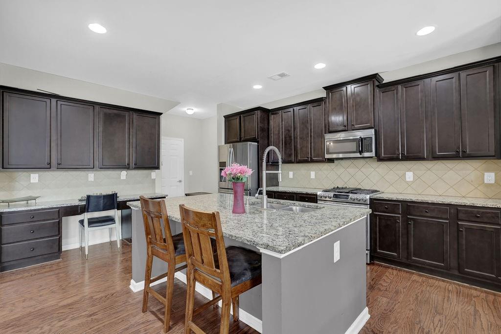 333 Nobleman Way Canton, GA 30114 - Photo 13 of 31 a kitchen with kitchen island granite countertop wooden cabinets a stove a sink and a center island