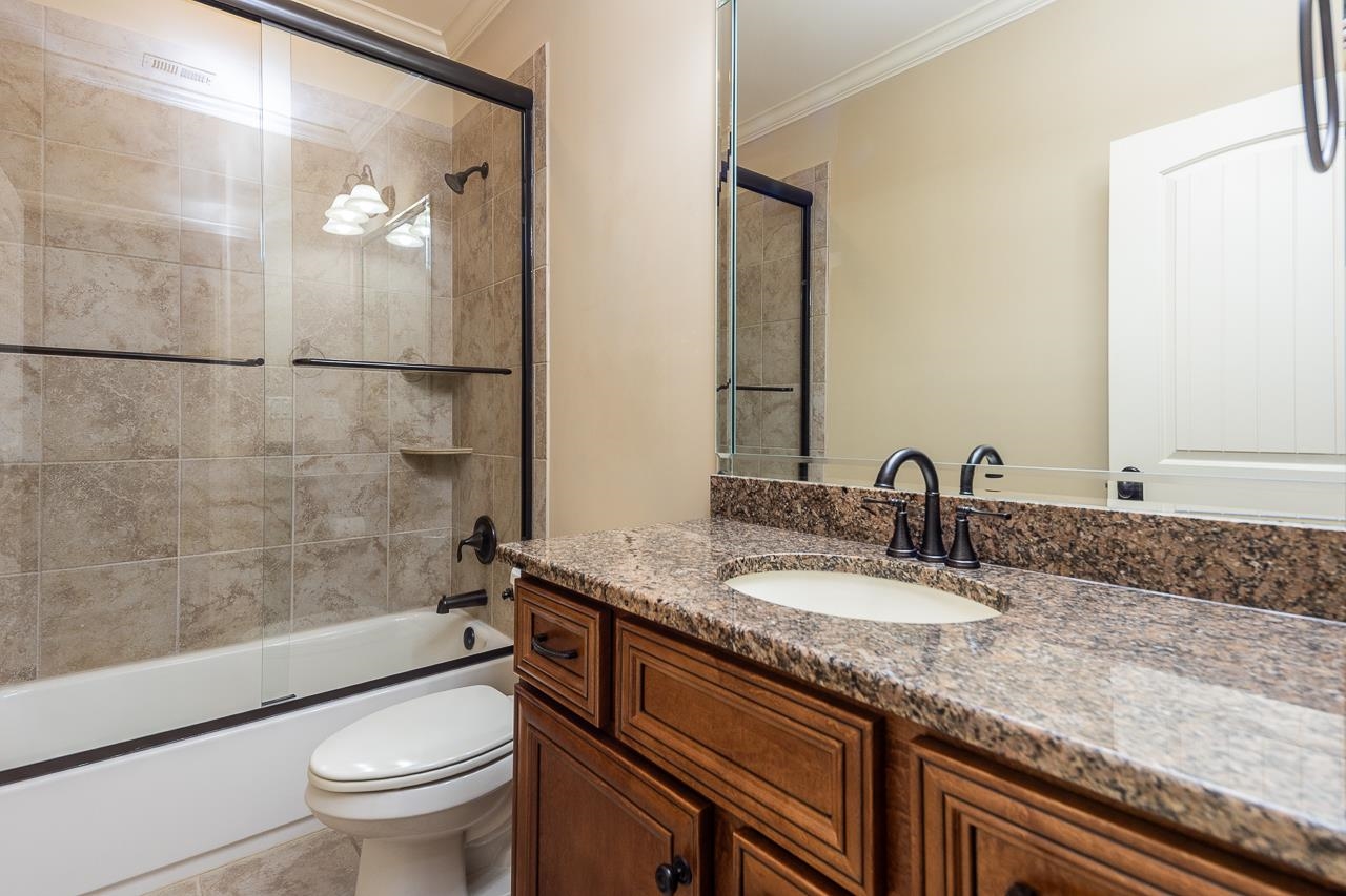 4600 Maple Glen Court Lakeland, TN 38002 - Photo 31 of 40 a bathroom with a granite countertop sink a toilet a mirror and shower