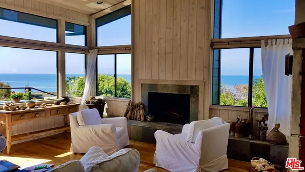 a living room with furniture large windows and a fireplace