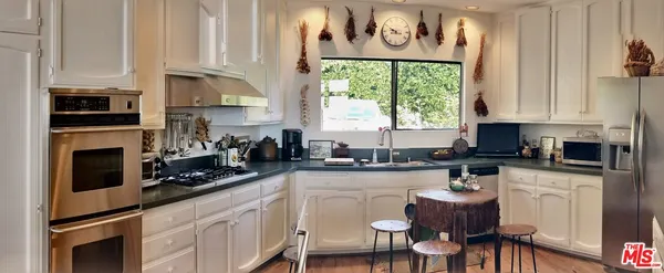 a kitchen with stainless steel appliances granite countertop a stove a sink and a white cabinets