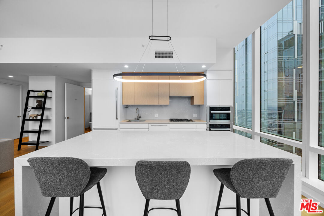 877 Francisco Street, Unit 1906 Los Angeles, CA 90017 - Photo 6 of 31 a kitchen with stainless steel appliances a table chairs and a refrigerator