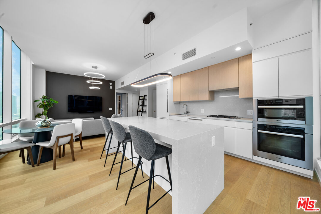 877 Francisco Street, Unit 1906 Los Angeles, CA 90017 - Photo 7 of 31 a kitchen with stainless steel appliances kitchen island a table and chairs in it