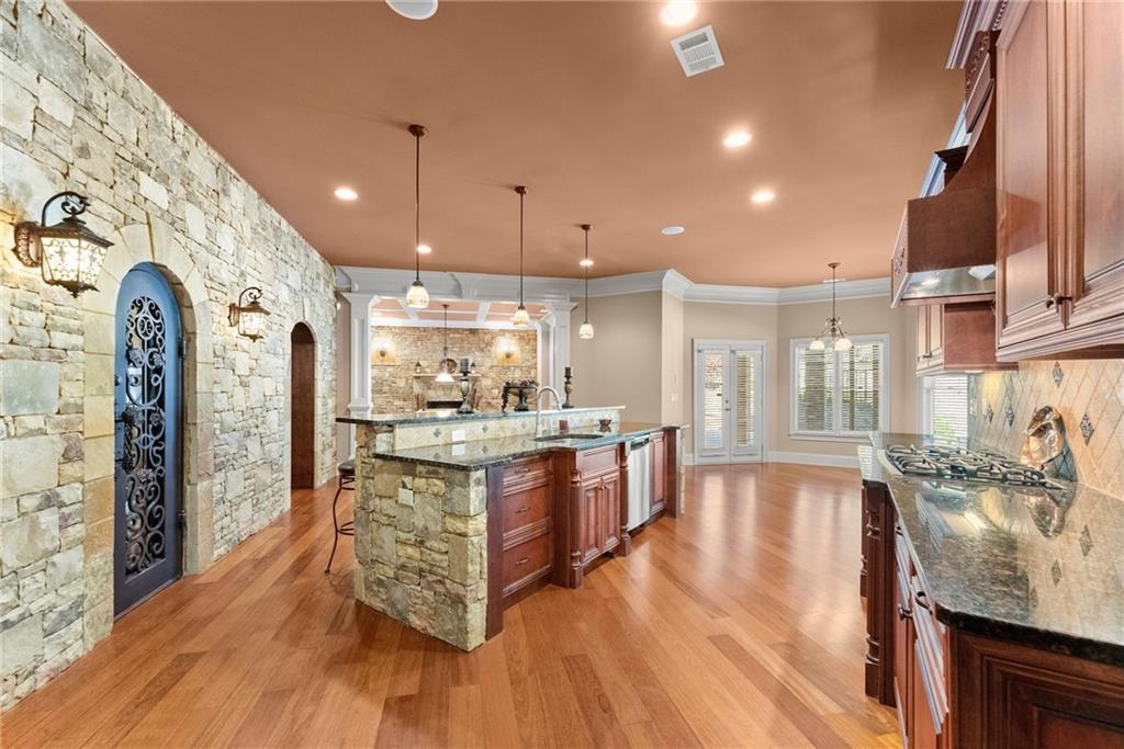 1310 Settles Road Suwanee, GA 30024 - Photo 50 of 71 a large kitchen with stainless steel appliances granite countertop a lot of counter space and wooden floors