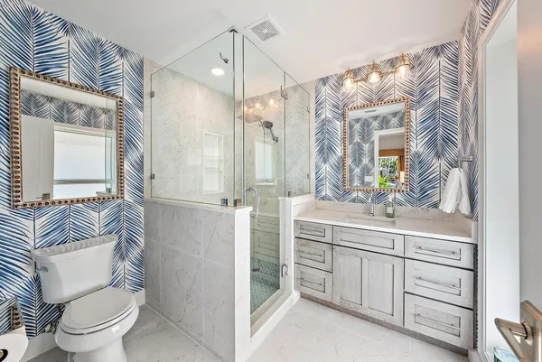 a bathroom with a sink a toilet a mirror and shower