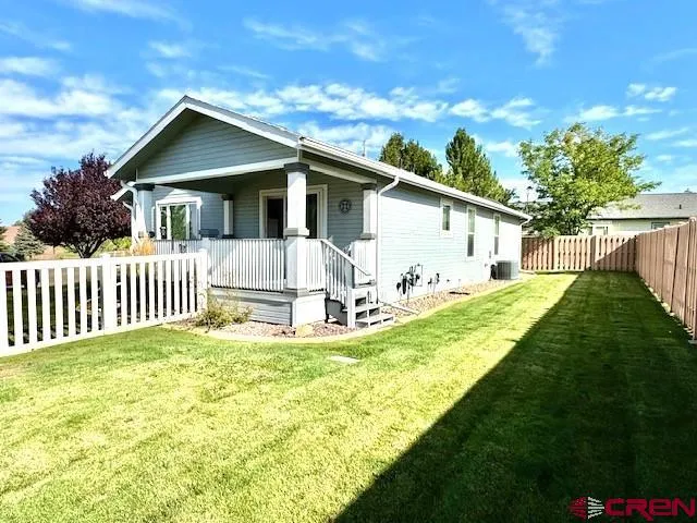 a white house that has a small yard and large trees