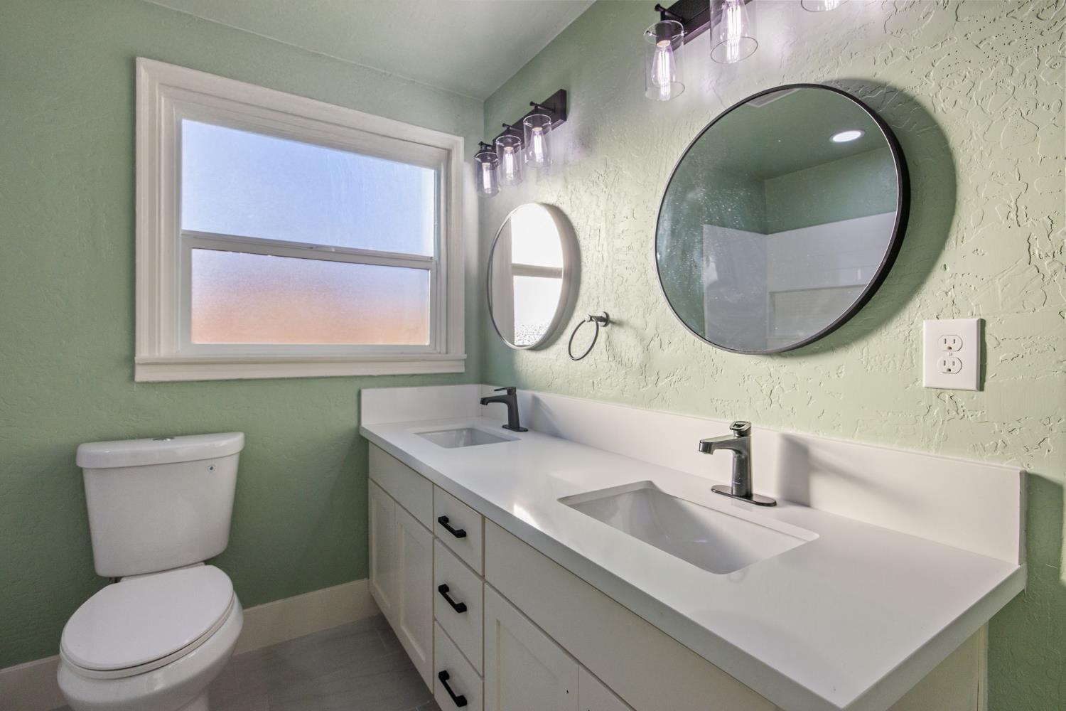 4722 East Florence Avenue Fresno, CA 93725 - Photo 35 of 51 a bathroom with a toilet a sink a mirror and toilet