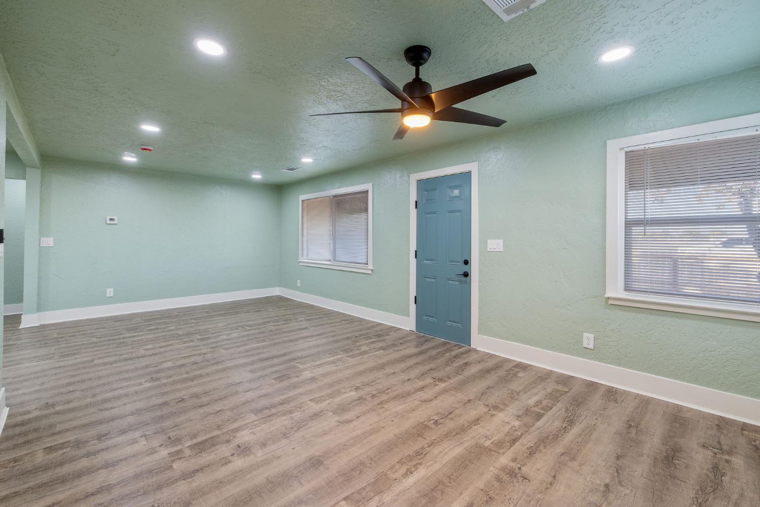 4722 East Florence Avenue Fresno, CA 93725 - Photo 8 of 51 an empty room with wooden floor fan and windows