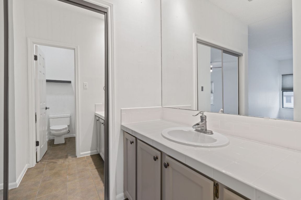 10819 Crown Colony Drive, Unit 22 Austin, TX 78747 - Photo 12 of 16 a bathroom with a sink a toilet and a mirror