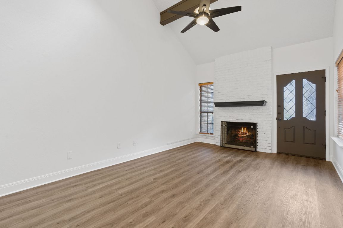 10819 Crown Colony Drive, Unit 22 Austin, TX 78747 - Photo 3 of 16 a view of an empty room with wooden floor fireplace and a window