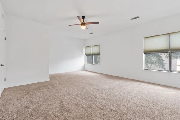 an empty room with windows and fan