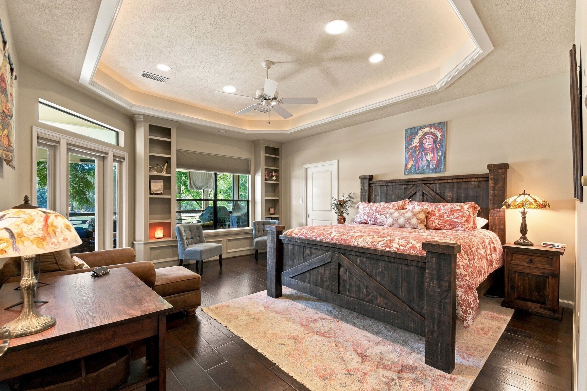 20341 Bay Hill Road Point Blank, TX 77364 - Photo 20 of 50 Second primary suite with tray ceiling, elegant wood flooring, and abundant natural light from large windows. Cozy sitting area and stylish built-in shelves add charm and functionality.