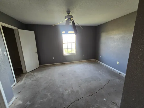 an empty room with windows and a ceiling fan