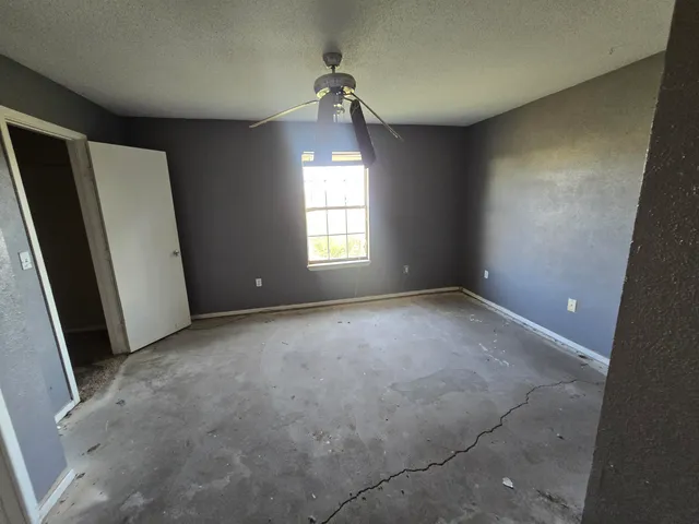 an empty room with windows and a ceiling fan
