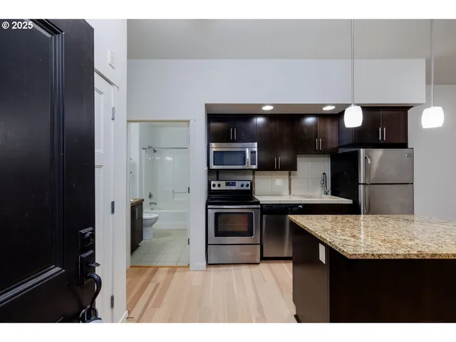 a kitchen with stainless steel appliances granite countertop a sink a stove and a microwave