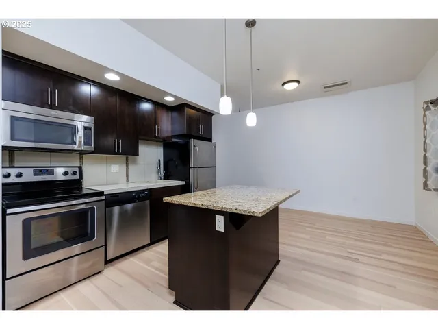 a kitchen with stainless steel appliances granite countertop a refrigerator a sink and a stove