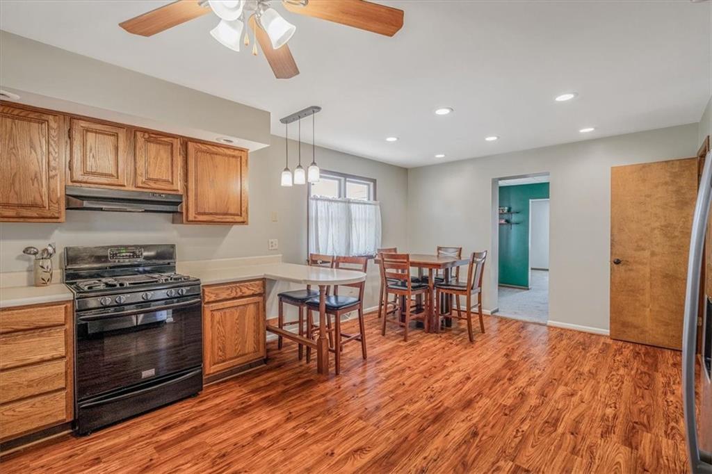 206 Washington Street Beaver, PA 15009 - Photo 17 of 32 a kitchen with stainless steel appliances granite countertop a stove top oven a sink dishwasher a dining table and chairs with wooden floor