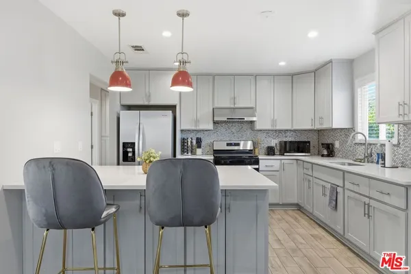 a kitchen with stainless steel appliances granite countertop a kitchen island a stove a cabinets a sink and a refrigerator