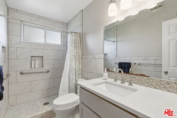 a bathroom with a sink toilet vanity and shower