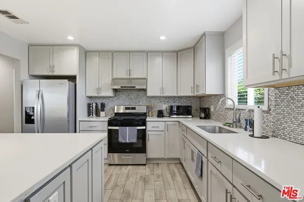 a kitchen with a sink a stove a refrigerator and cabinets