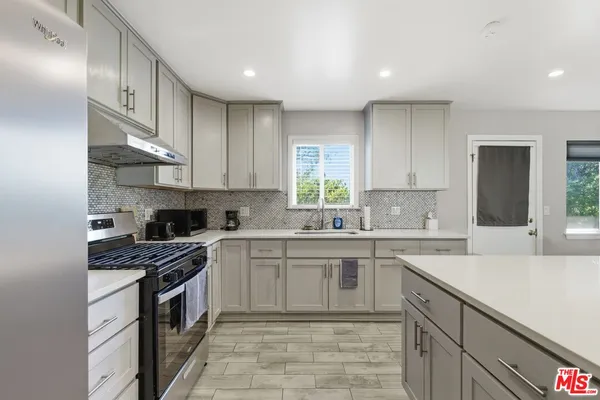 a kitchen with a sink white cabinets and appliances
