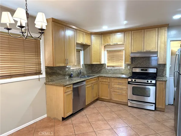 a kitchen with stainless steel appliances granite countertop a stove a sink and a refrigerator