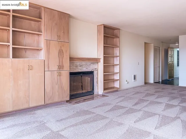 a view of an empty room with a fireplace and cabinet