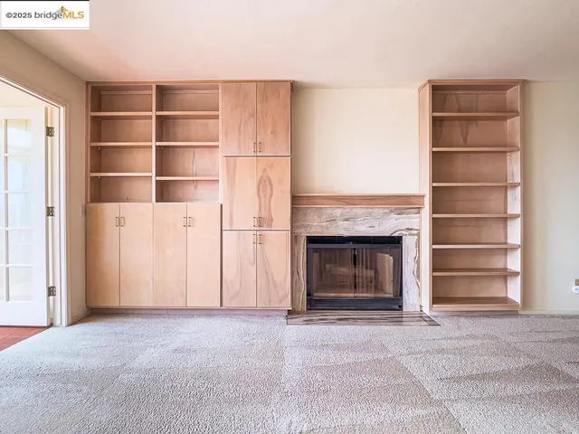 a view of an empty room with a fireplace and a window
