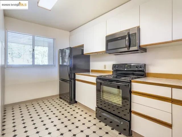 a kitchen with stainless steel appliances kitchen island granite countertop a stove a microwave and a refrigerator