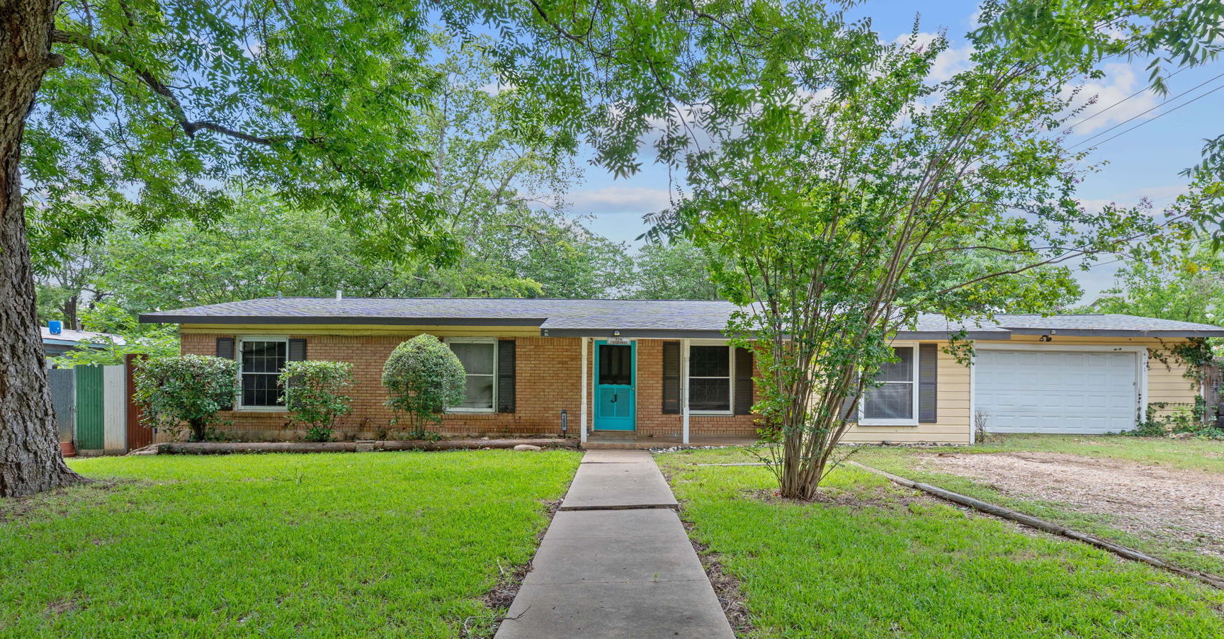 10000 Gail Road Austin, TX 78748 - Photo 1 of 1 Ranch-style home with a garage, dirt driveway, brick siding, and a front lawn