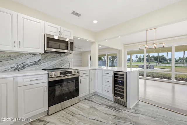 a kitchen with granite countertop a refrigerator and white cabinets