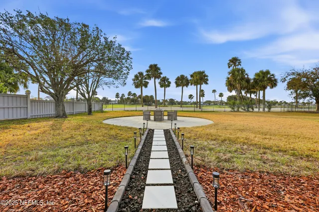 a view of a swimming pool with a garden and palm trees
