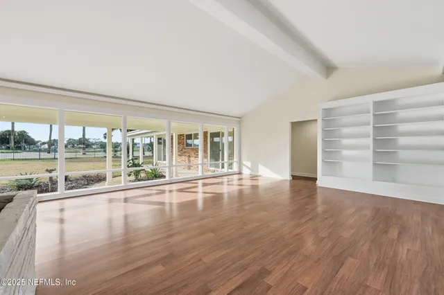 a view of empty room with wooden floor and floor to ceiling window