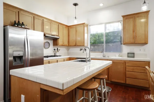a kitchen with stainless steel appliances granite countertop a sink a stove a refrigerator and island