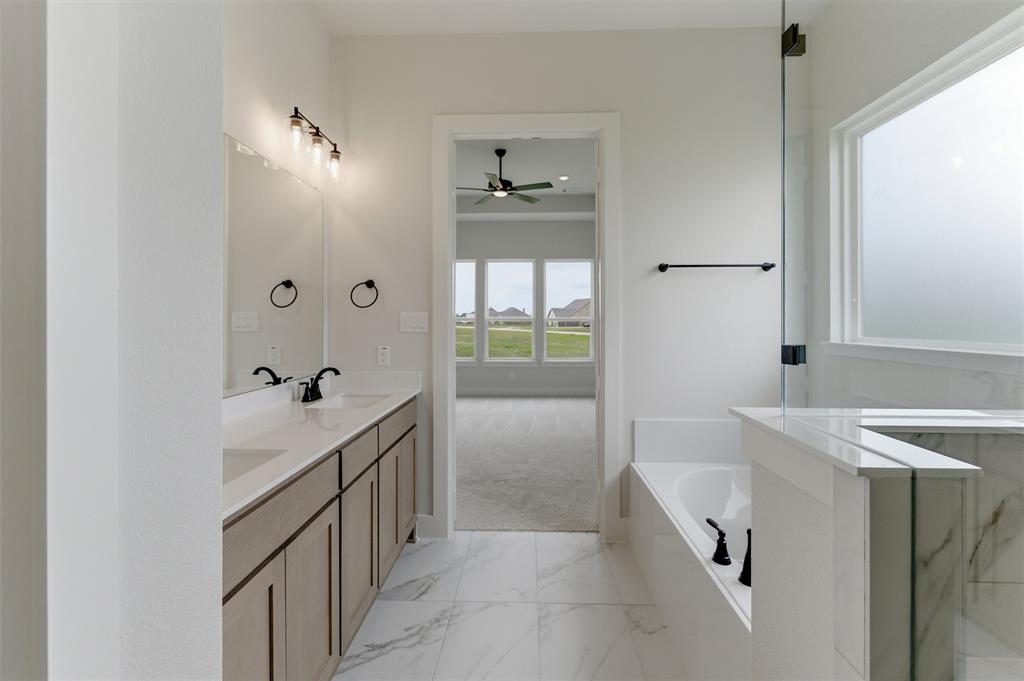2204 Continent Court Krum, TX 76249 - Photo 13 of 28 Spacious bathroom featuring a double vanity with stone countertops, undermount sinks, and matte black fixtures