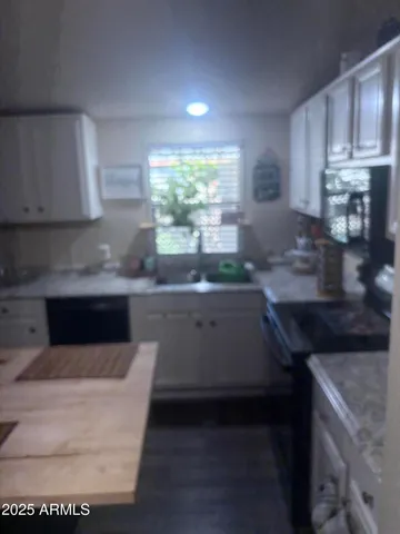 a kitchen with kitchen island granite countertop a sink cabinets and stainless steel appliances