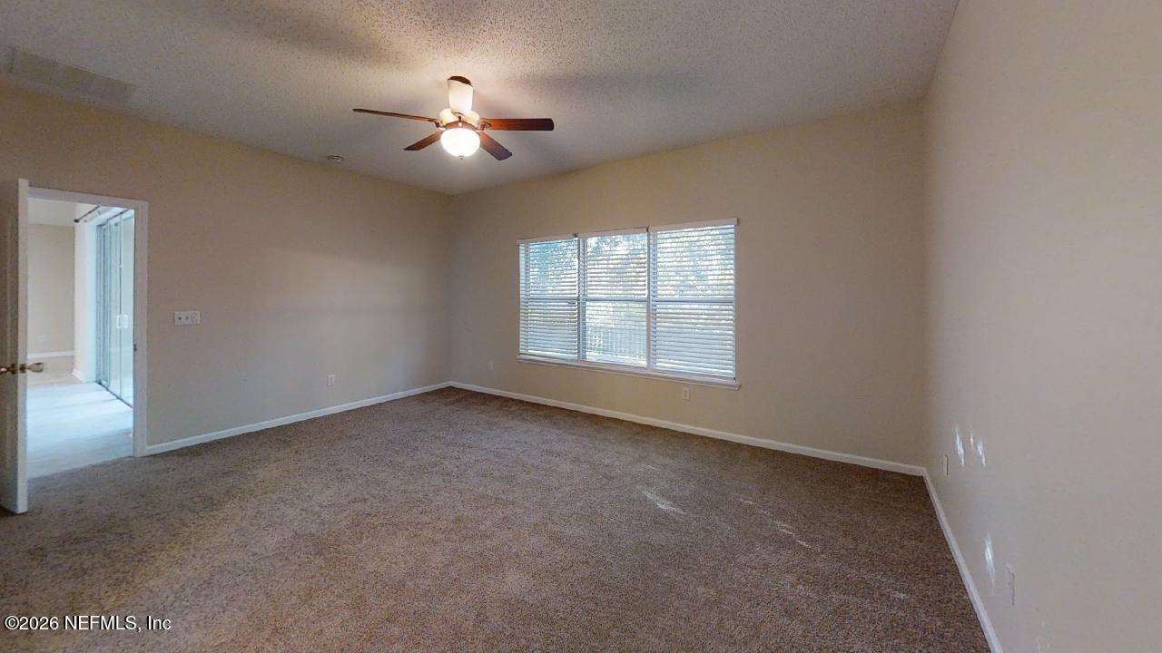 14454 Millhopper Road Jacksonville, FL 32258 - Photo 23 of 44 an empty room with chandelier fan and windows