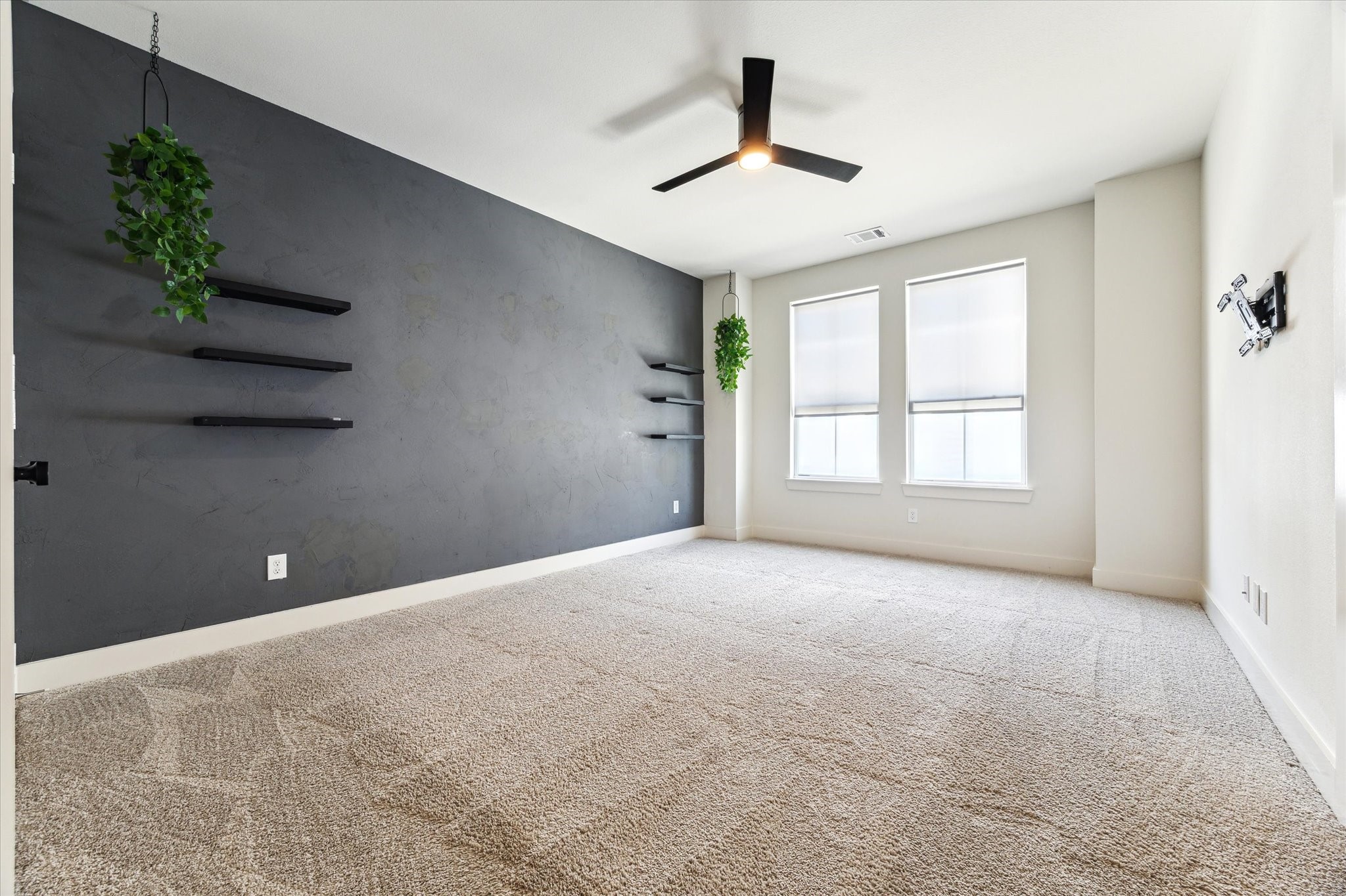 4155 Griggs Road Houston, TX 77021 - Photo 8 of 17 Spacious primary retreat exudes style with a bold accent wall, chic floating shelves, soaring ceilings, and streaming natural light. Plush neutral carpet adds the perfect touch of softness to this bright, modern escape.