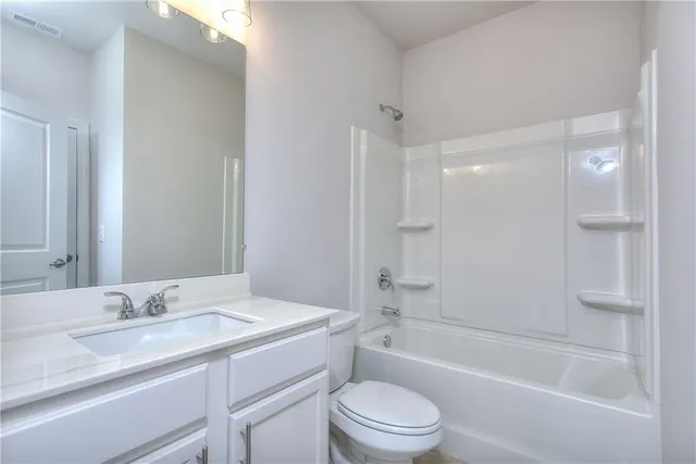 a bathroom with a granite countertop sink a toilet and shower