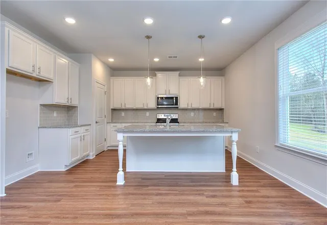 a view of kitchen with granite countertop refrigerator oven sink and white cabinets with wooden floor