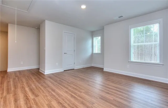 a view of an empty room with wooden floor and a window