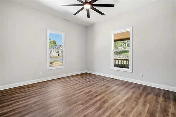 a view of an empty room with window and wooden floor