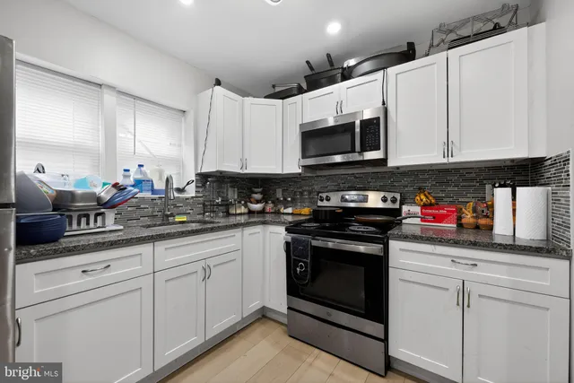 a kitchen with stainless steel appliances granite countertop white cabinets sink and stove