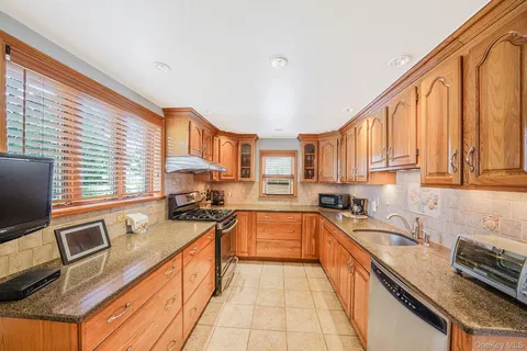 a kitchen with a sink a counter top space cabinets stainless steel appliances and a window
