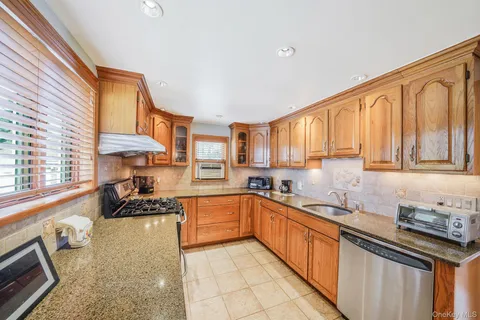 a kitchen with stainless steel appliances a sink stove cabinets and a window