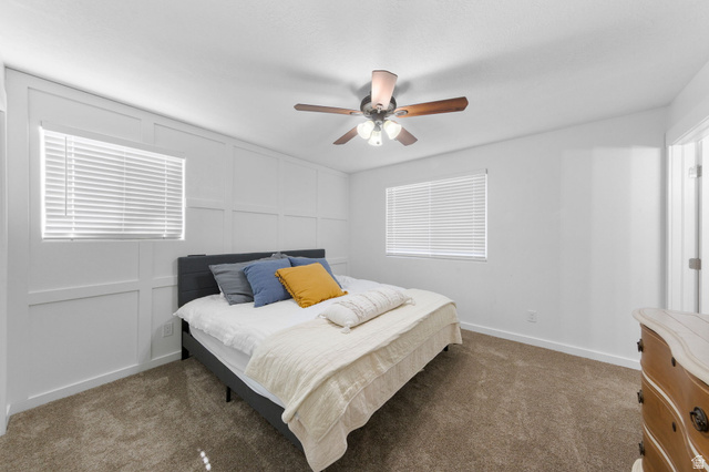 664 East Springhill Drive Washington, UT 84780 - Photo 13 of 21 Room featuring a decorative accent wall with paneling, two windows with blinds, a ceiling fan with light fixture, and neutral carpet flooring