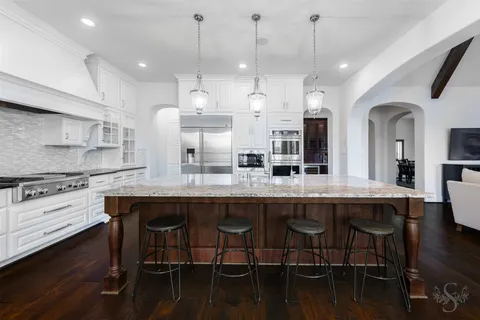 a kitchen with stainless steel appliances granite countertop a table chairs stove and kitchen island