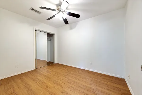 an empty room with wooden floor and ceiling fan